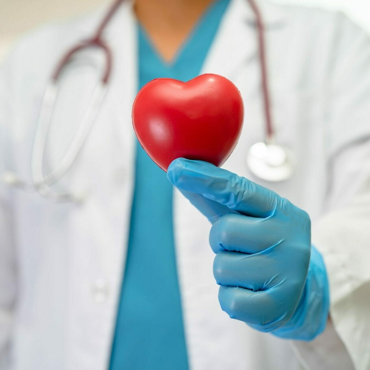 Doctor holding red heart in nursing hospital for good health.